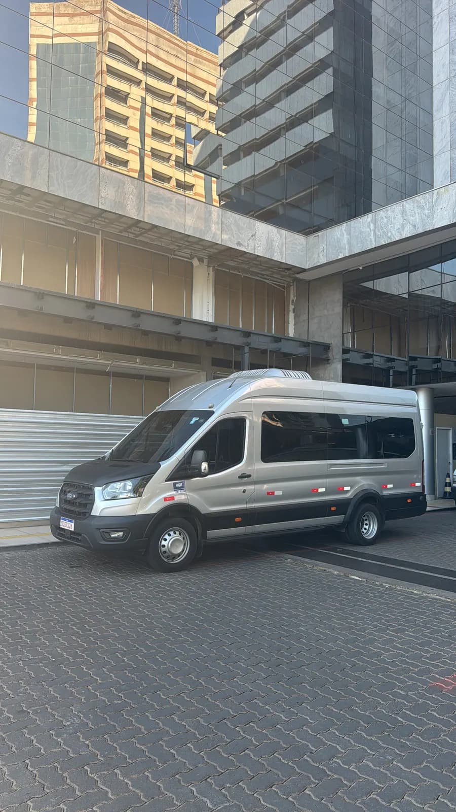 Van executiva prata da Auge estacionada em frente a um prédio comercial